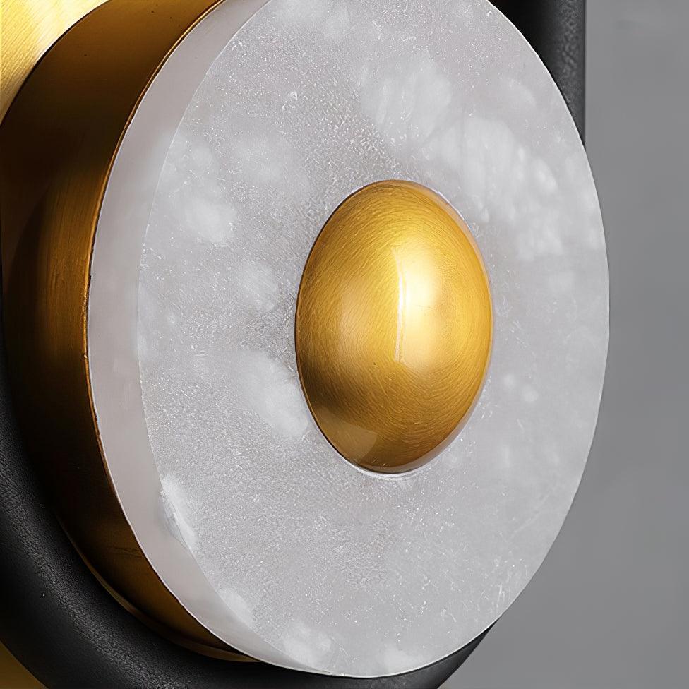 Angled close-up of white stone-textured ring and brushed gold centre dome, with larger gold disc behind