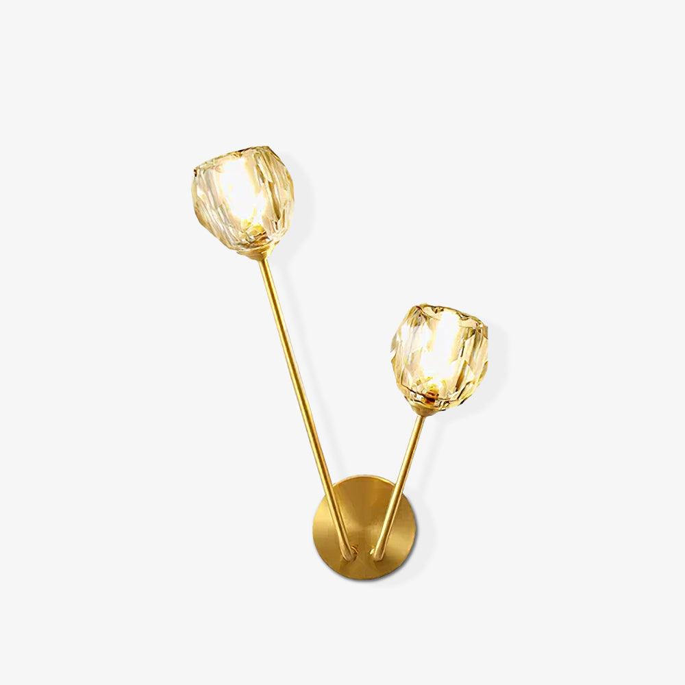 Small isolated view of lit faceted glass wall light with unequal brass-tone stems on white background