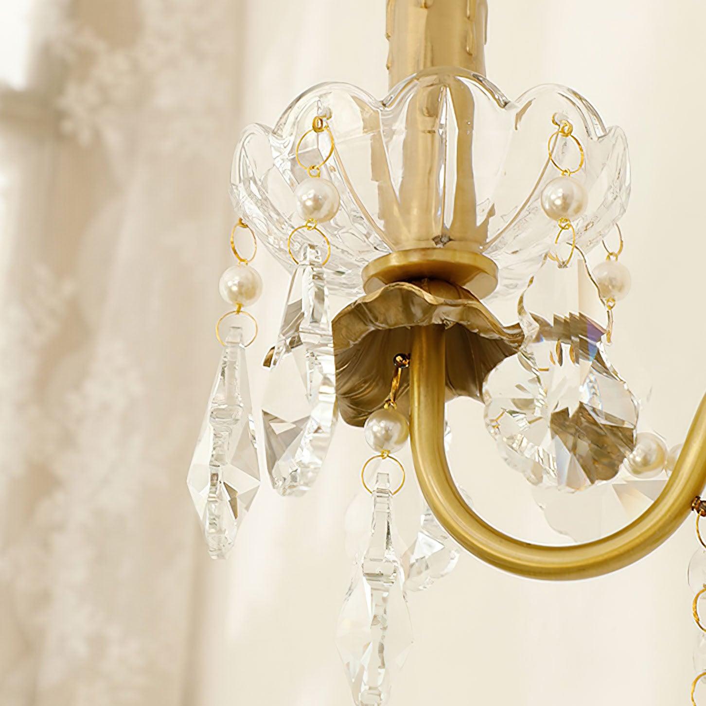 Close-up of clear scalloped bowl around gold holder, pale round beads, linked rings and faceted teardrop-shaped drops