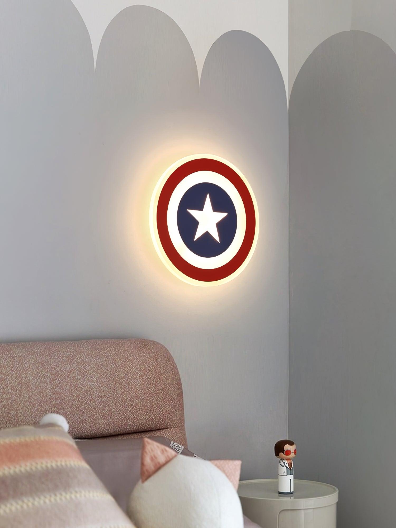 Red-ring and blue-centred star light on scalloped wall above pink bedhead and round bedside table