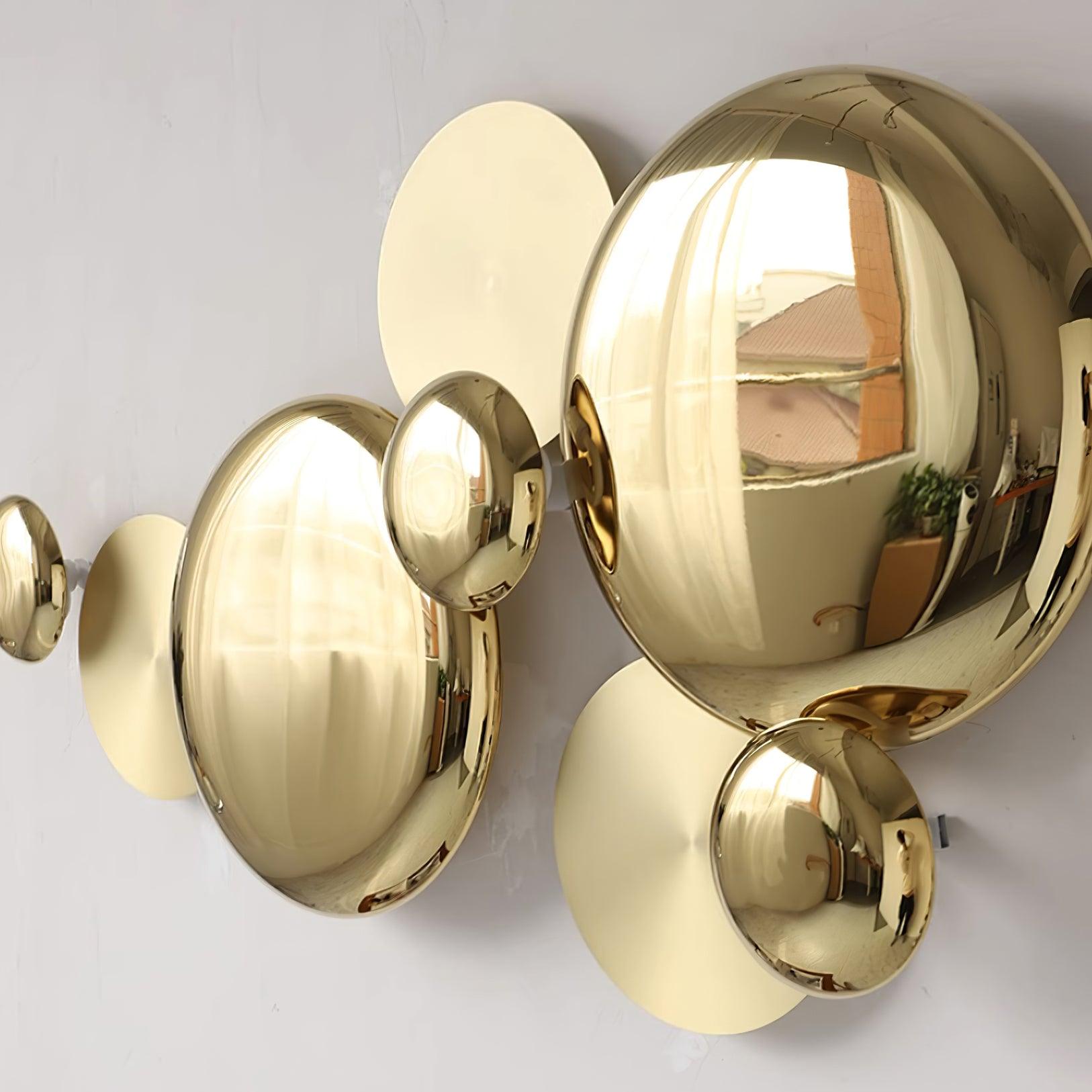 Close side detail of the reflective gold-tone faces and flatter discs, showing reflections of a nearby window