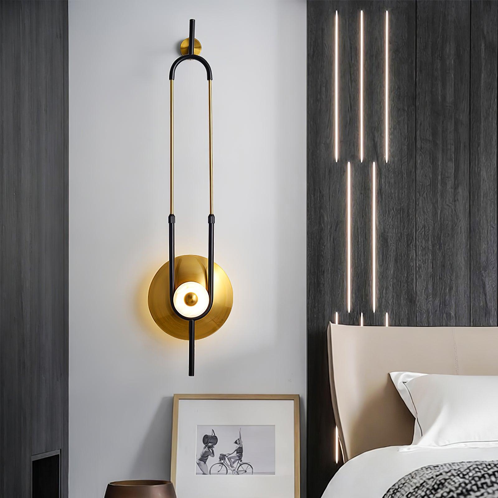 Tall gold-and-black wall light beside beige headboard and dark wall panel with separate vertical light strips