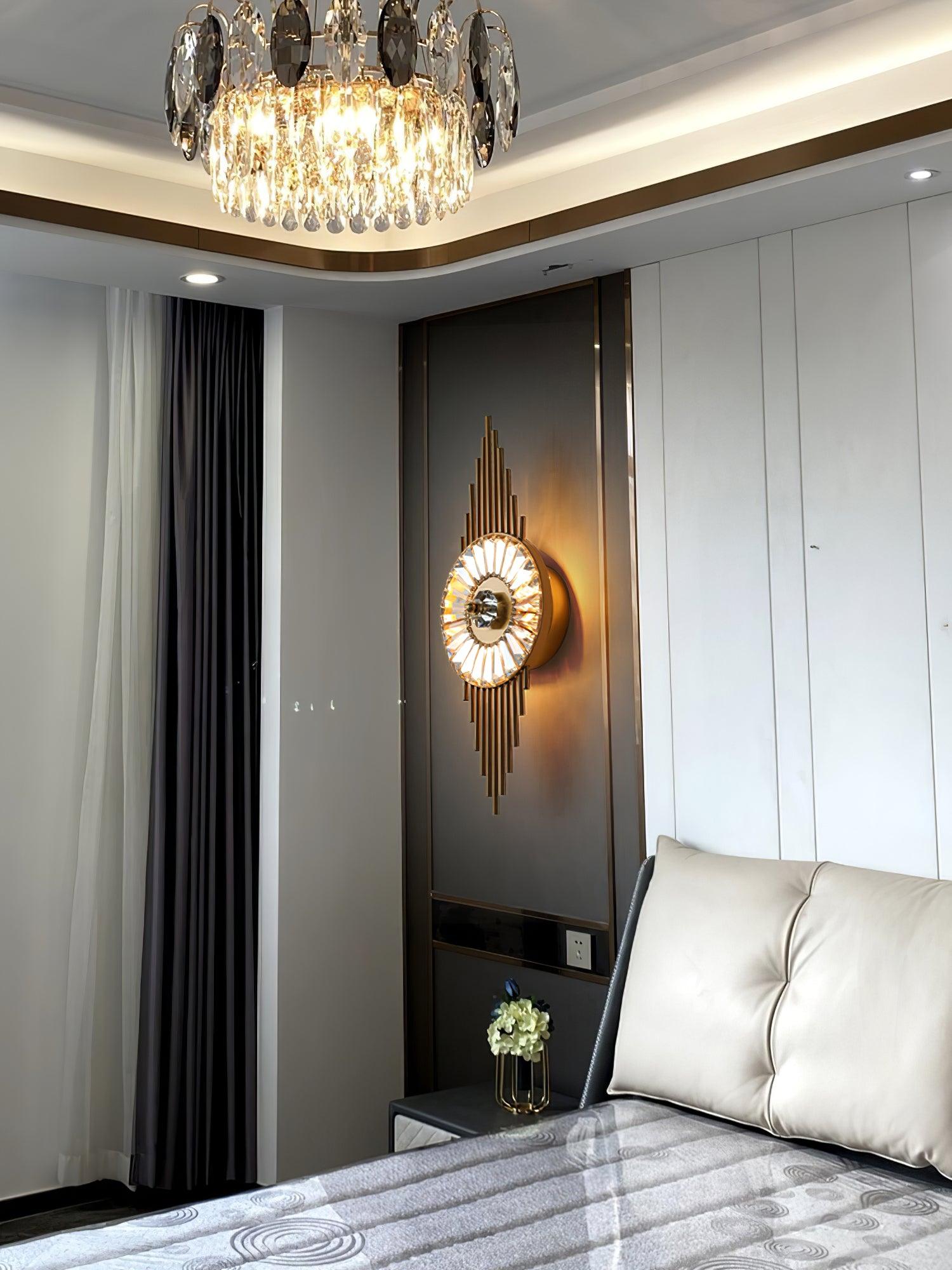Gold crystal glass wall lamp on a dark bedroom panel beside a white headboard and curtains
