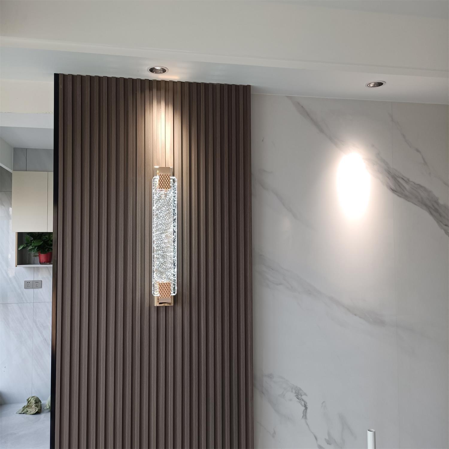 White-glowing crystal wall light on a dark slatted panel beside a pale marble-look wall