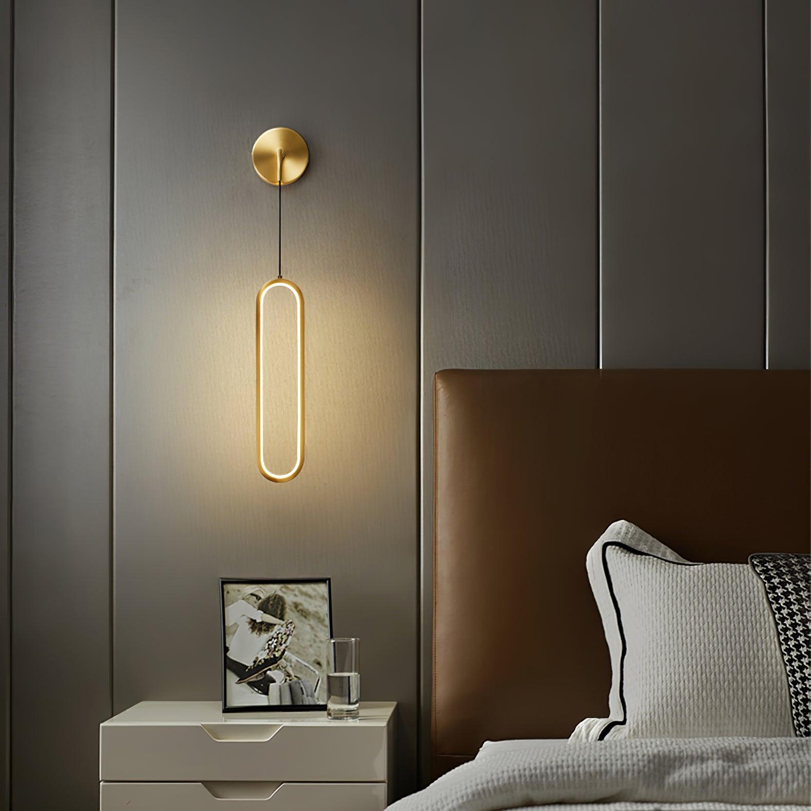 Brass wall plate and hanging oval ring beside a bed