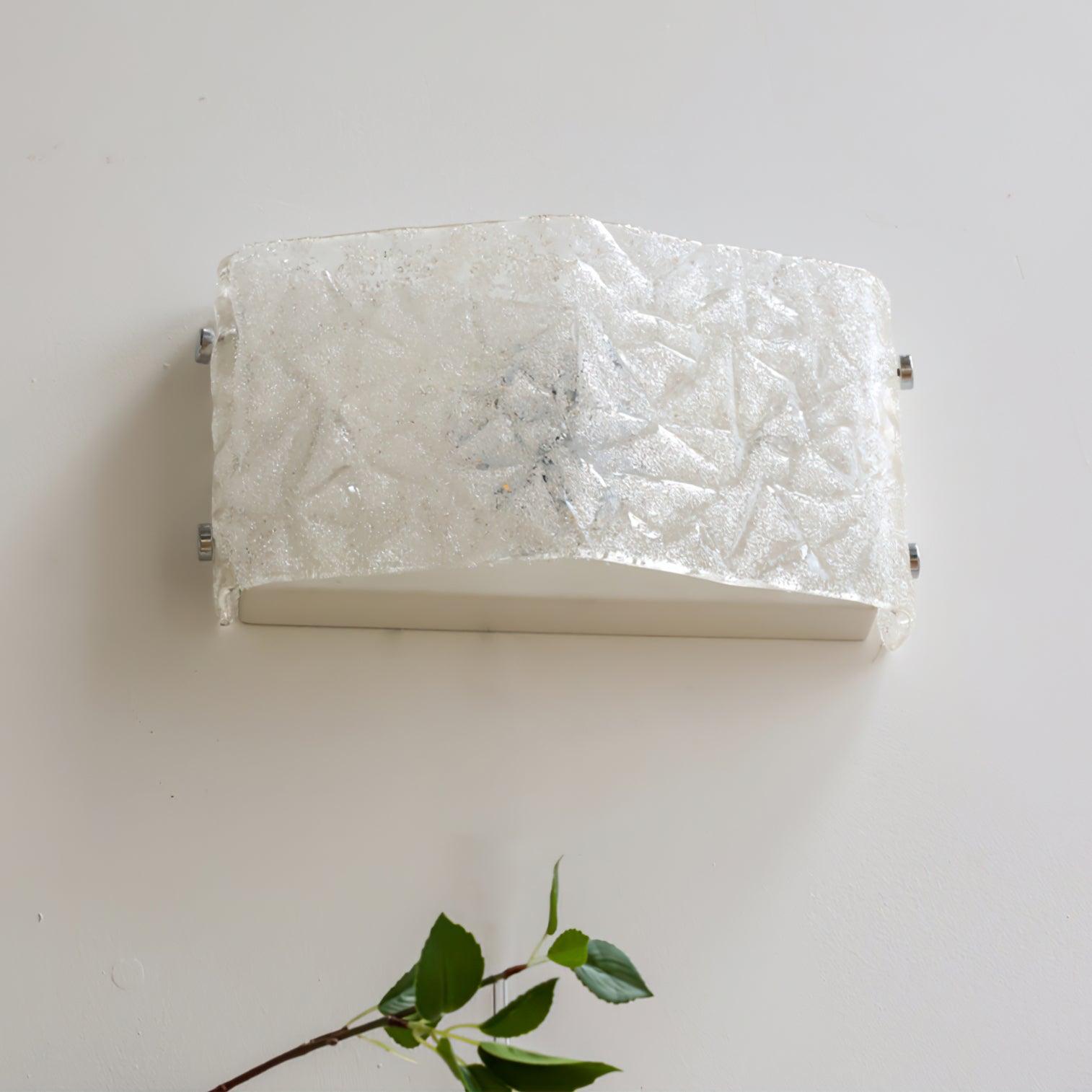 Low-angle view of white textured glass wall light showing the underside housing and chrome edge fasteners