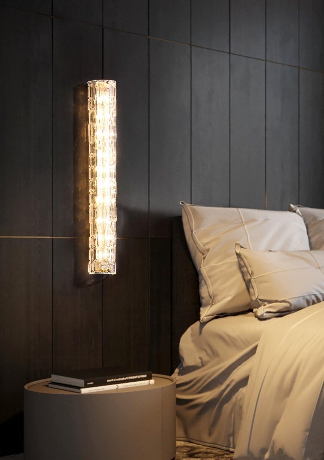 Fine Art sconce beside a bed and round bedside table