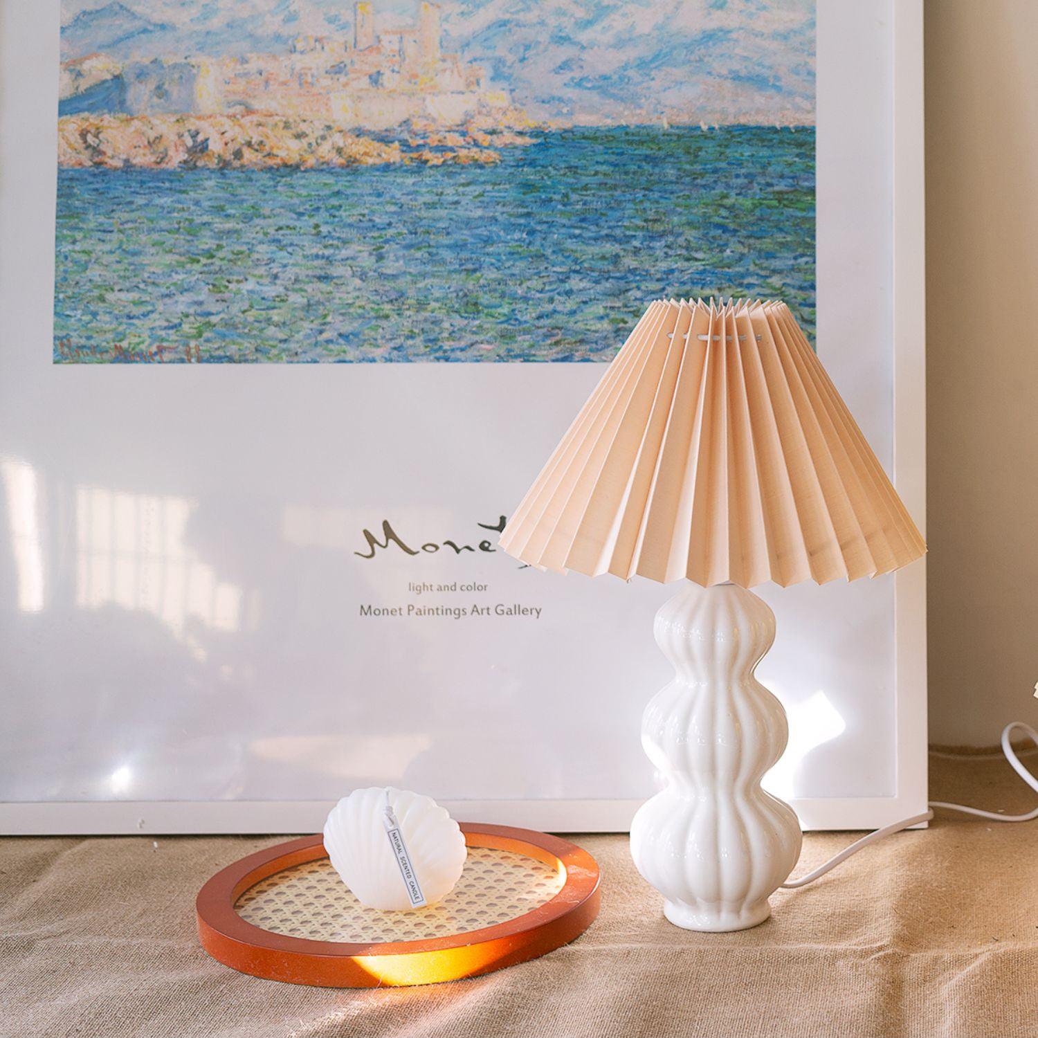 Leo lamp with a peach-colour shade beside framed landscape art