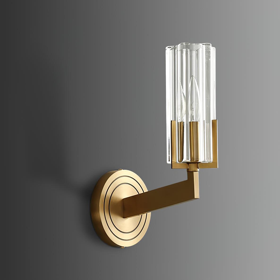 Unlit single-shade Kayla angled right from brass circular mount on grey wall, showing candle bulb through clear fluted glass
