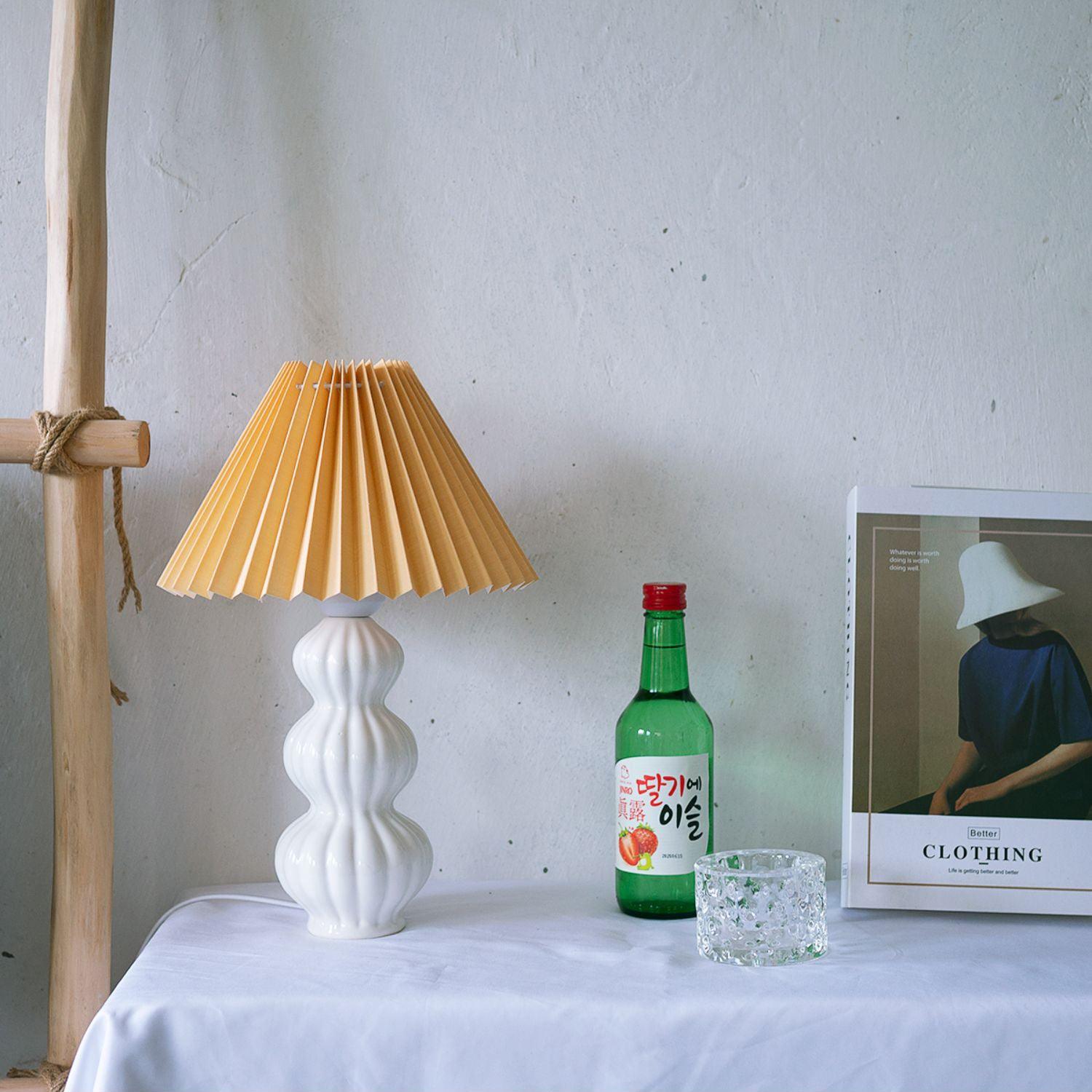 Leo lamp with an ochre pleated shade and white ribbed ceramic body