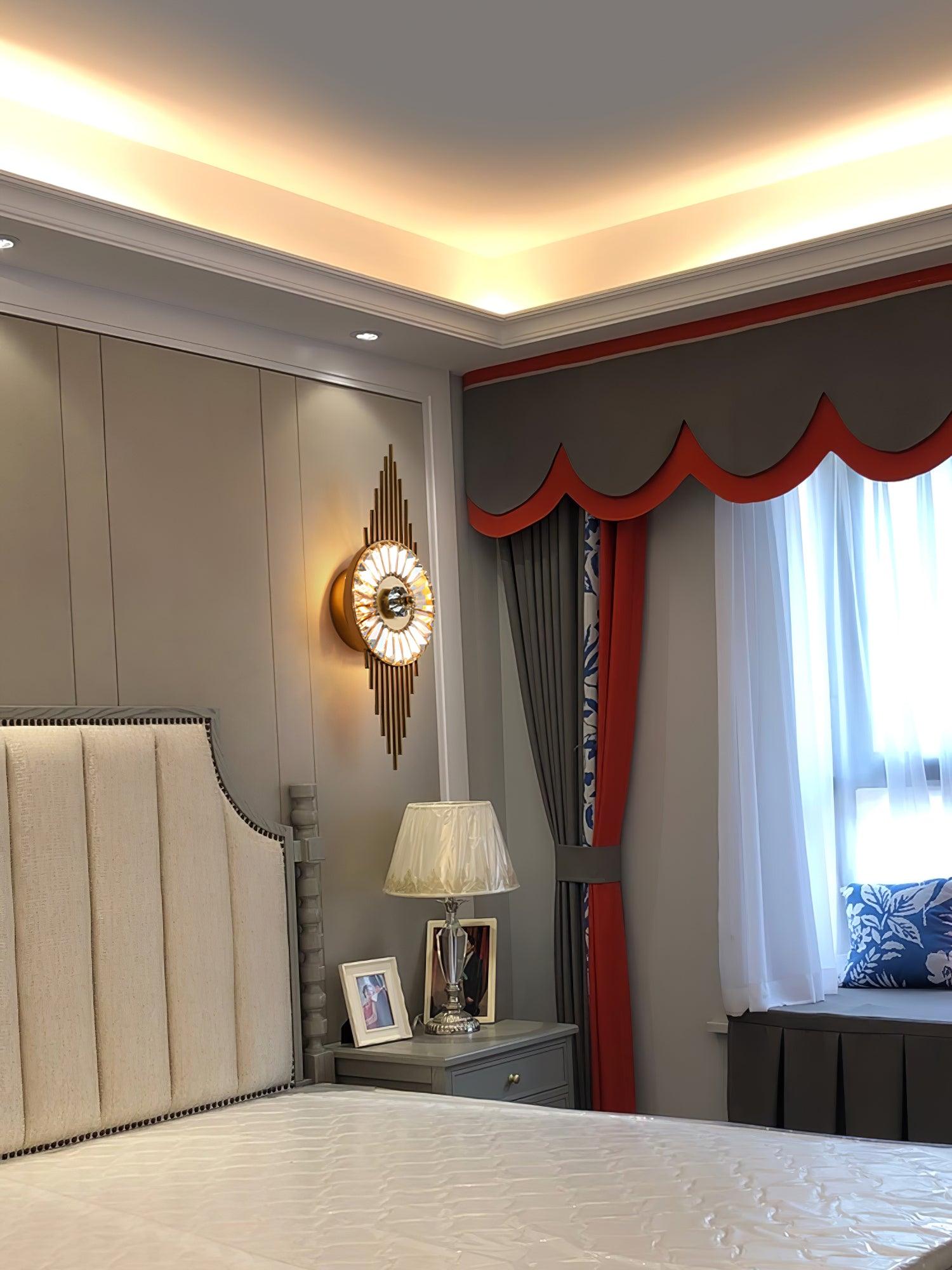 Crystal Gear wall lamp beside a tall upholstered headboard, bedside table and curtained window
