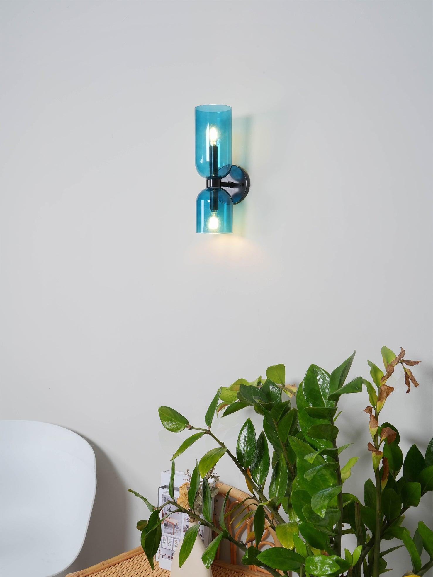 Blue glass wall fixture beside a living-room plant