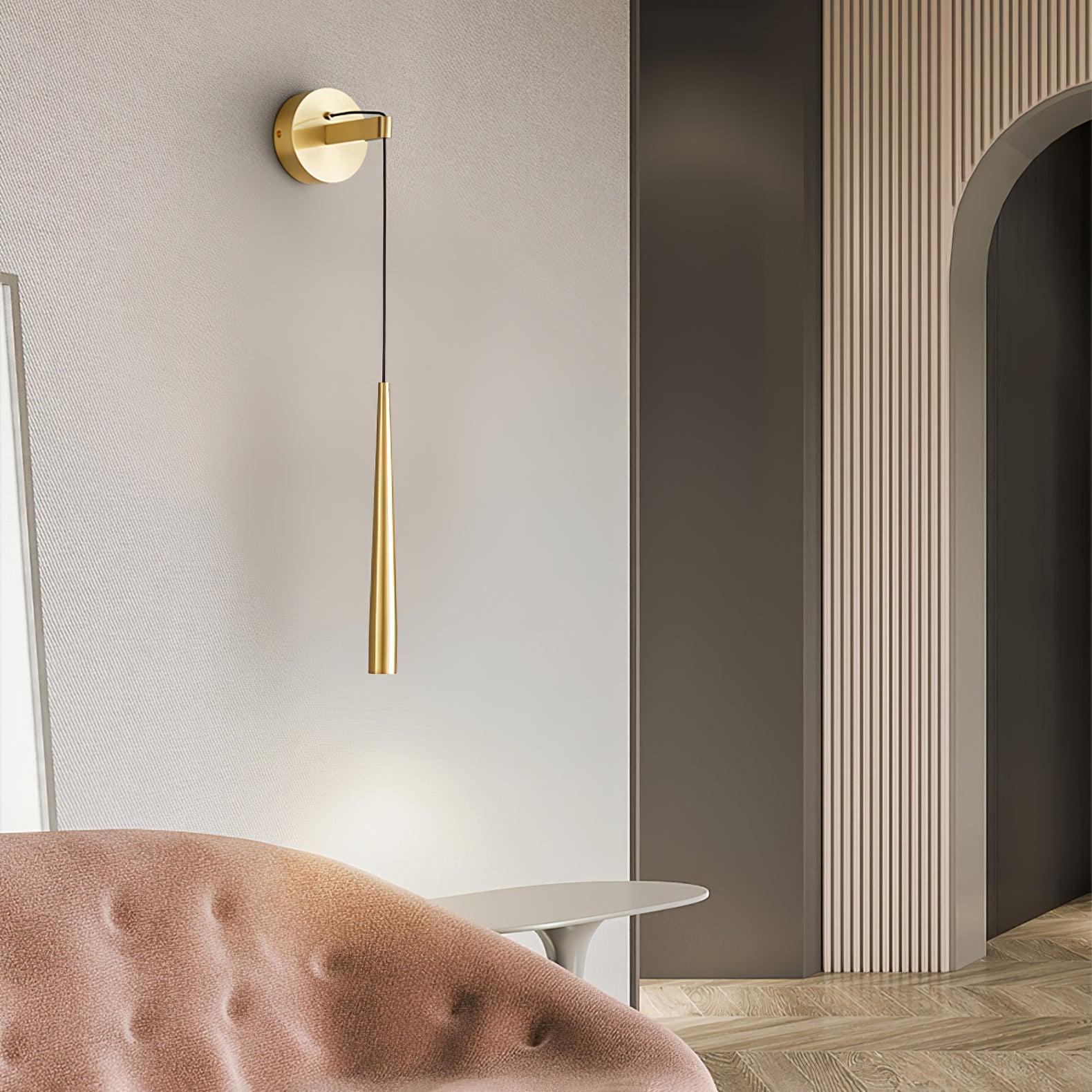 Slim brass-tone plain cone beside a pink chair and small side table near a dark arched doorway