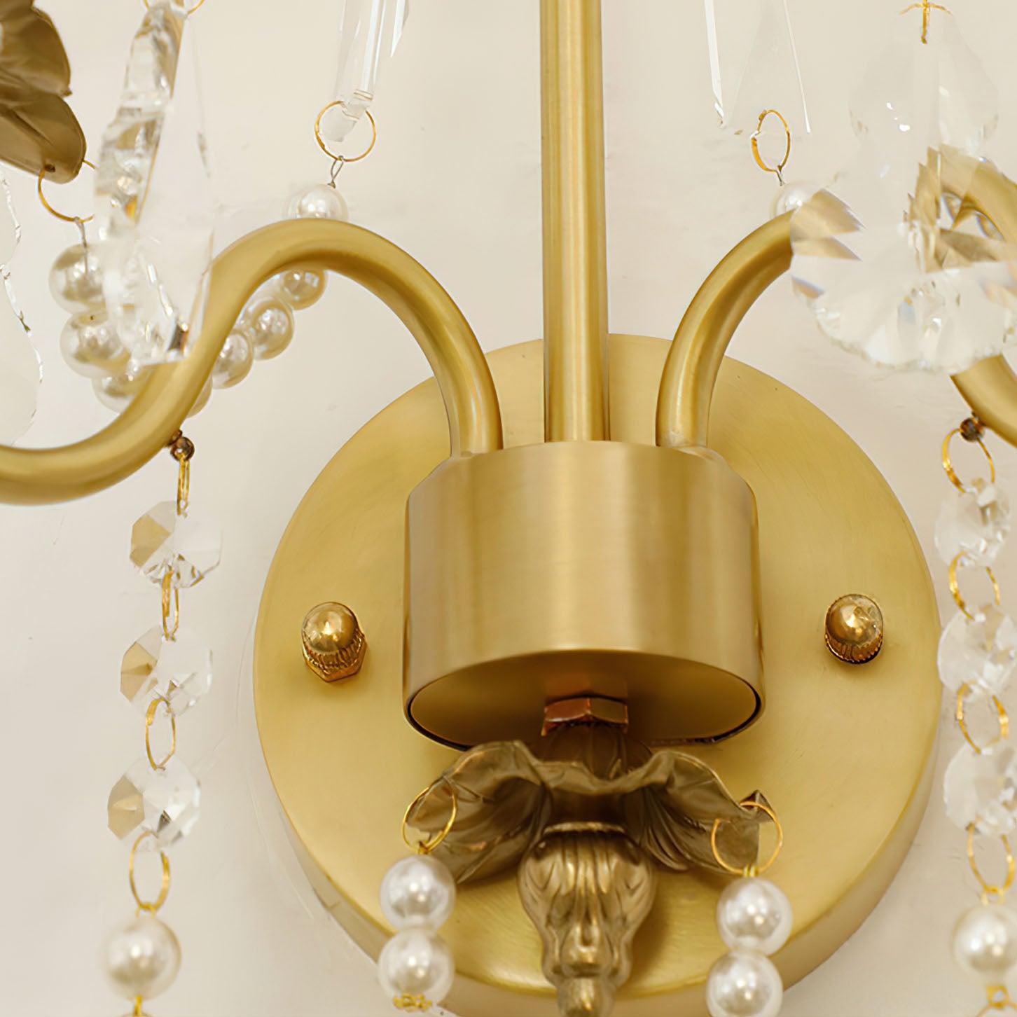 Close-up of round gold wall plate with two domed fasteners, central hub, curved arms and lower scalloped metal detail