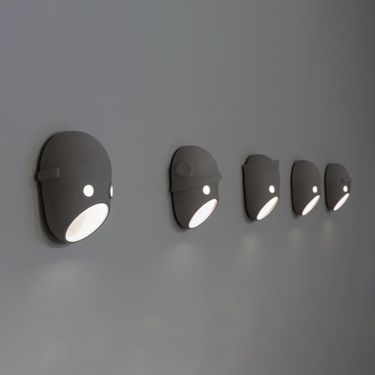 Five face wall lights viewed along a grey wall