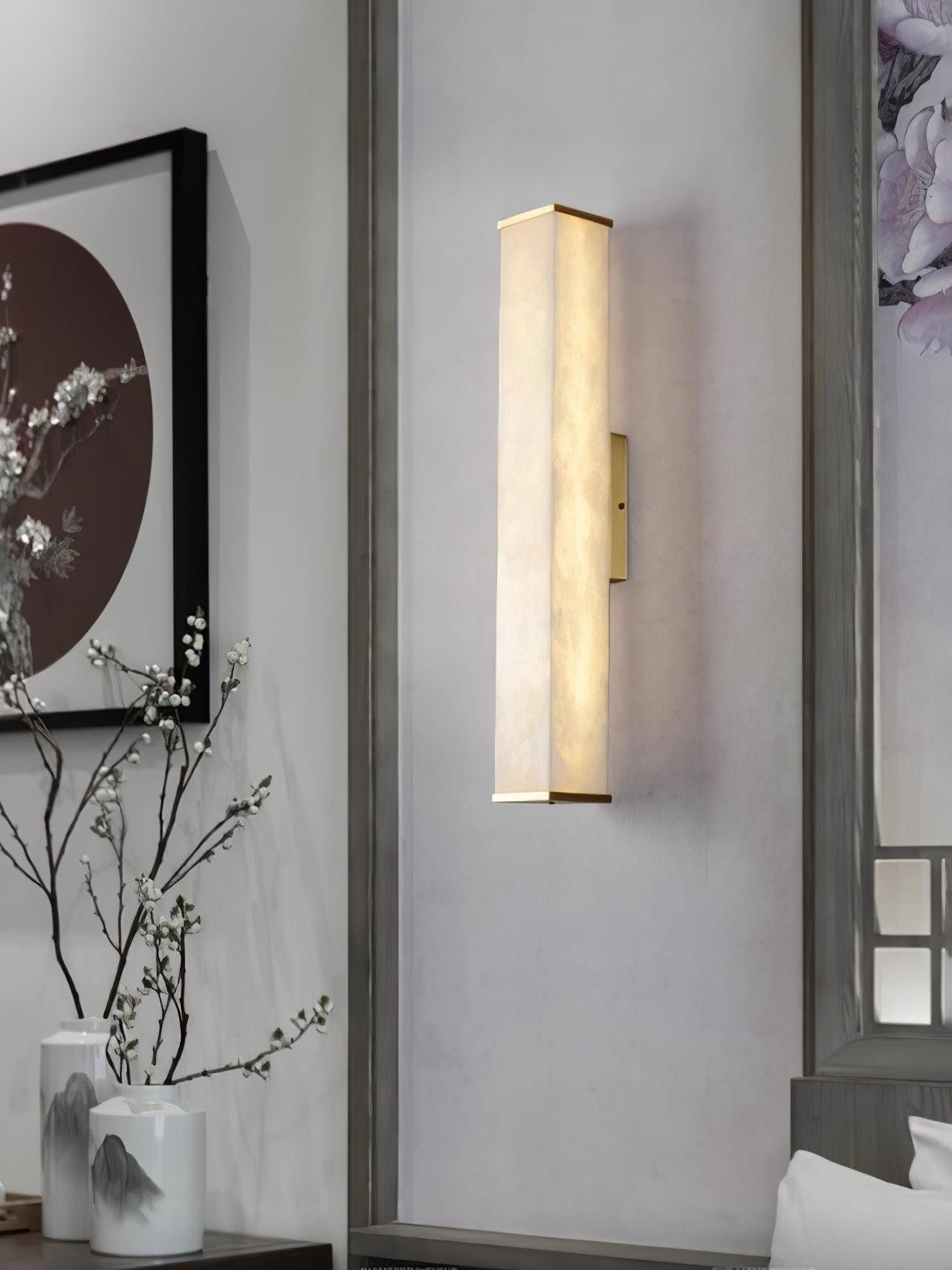 Glowing alabaster wall light on an inset panel beside red-circle artwork, white vases and flowering branches