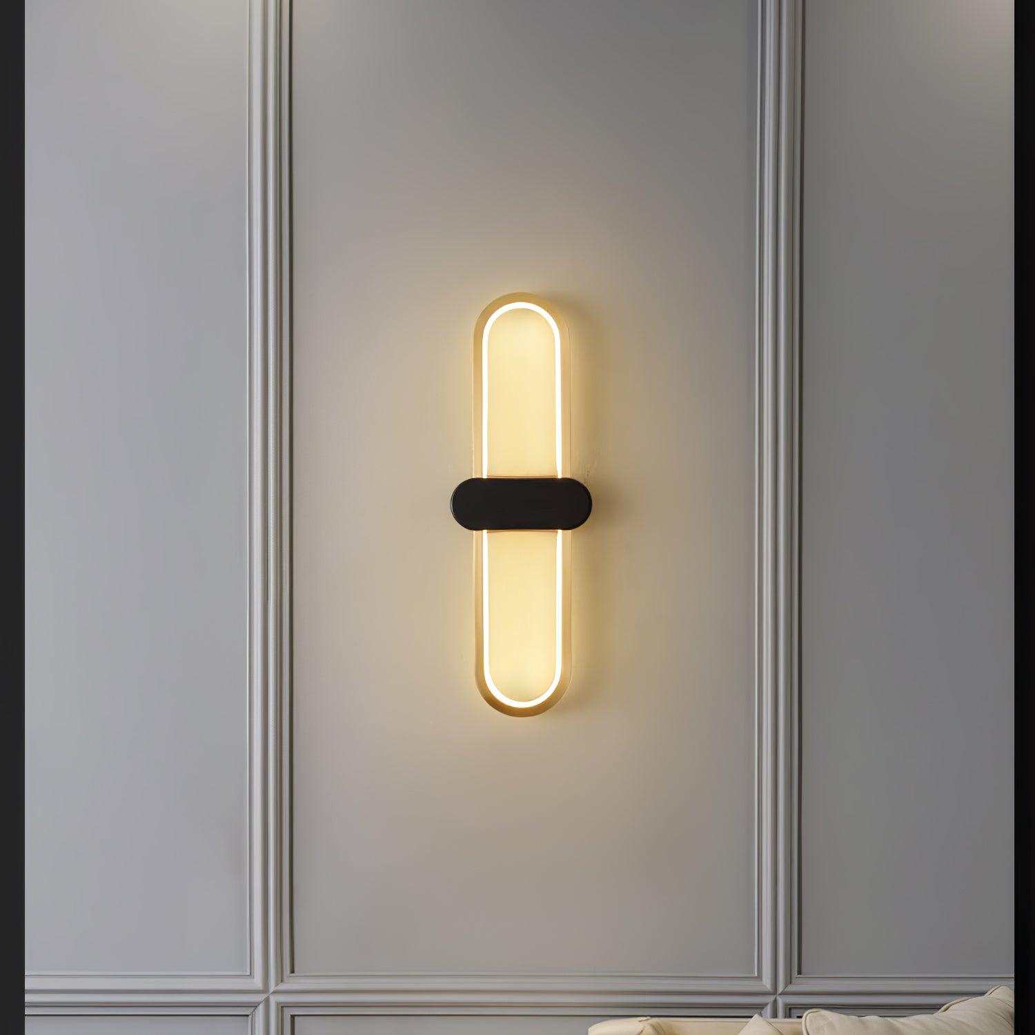 Gold oval loop and black-centre wall light within decorative pale wall panelling