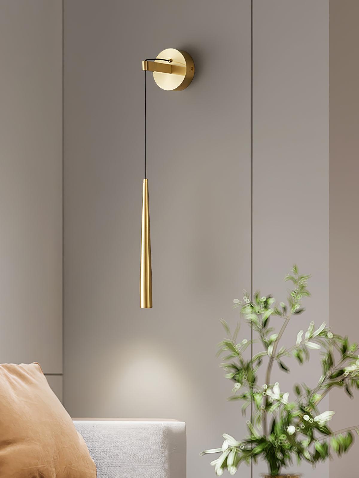 Close sofa-side view of a brass-tone plain-ended cone with a thin black cable and round plate