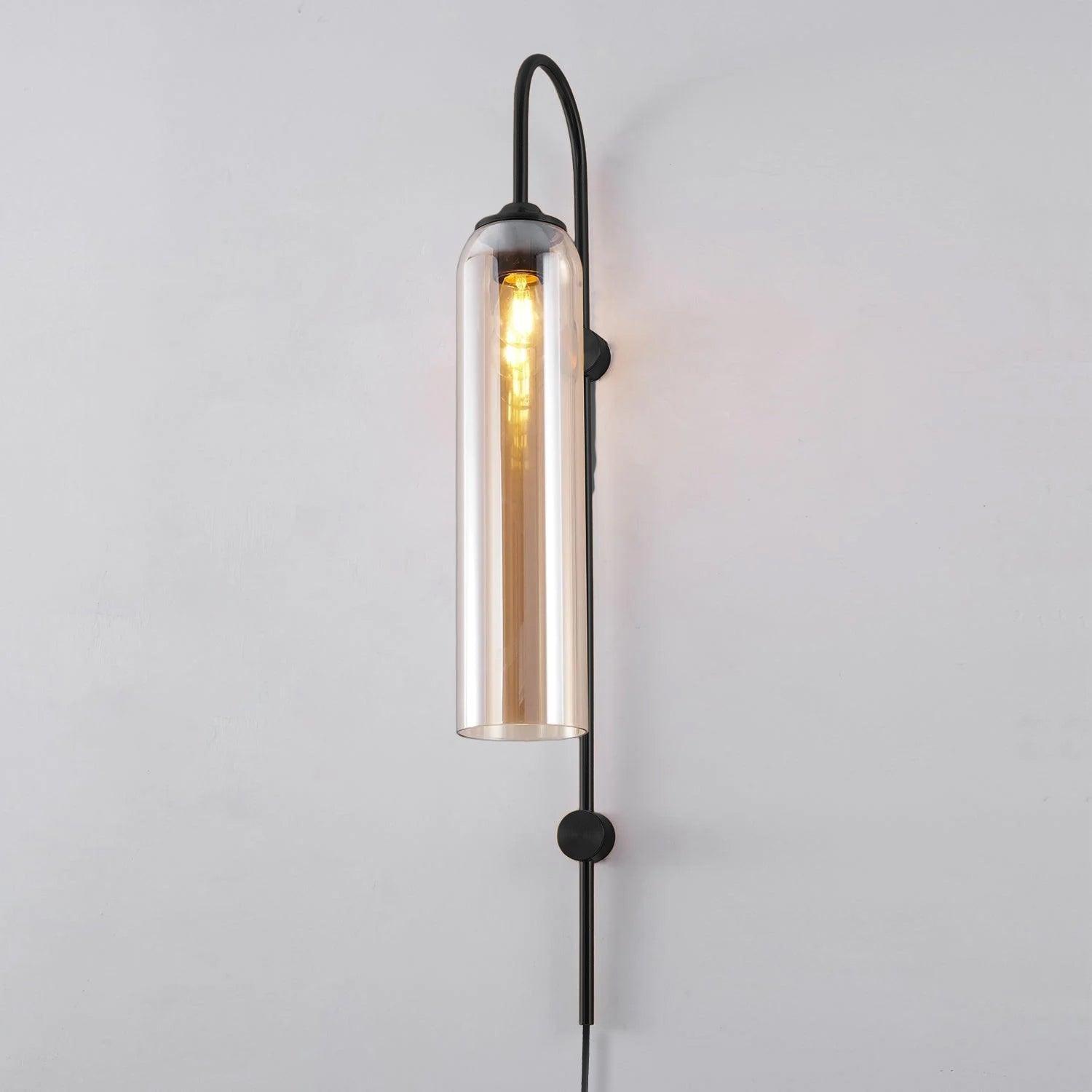 Illuminated amber-toned glass tube on a black wall stem