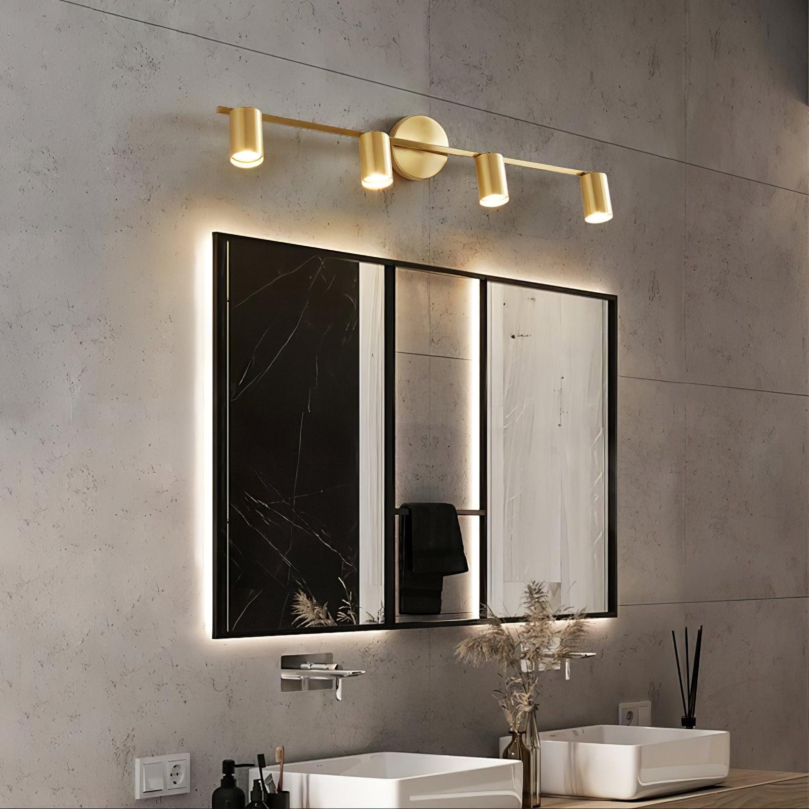 Brass-tone four-head wall spotlight above rectangular mirrors and two white basins