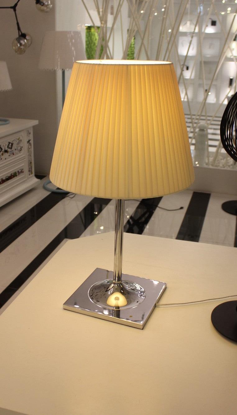 Table lamp with a yellow pleated-looking shade and reflective square base