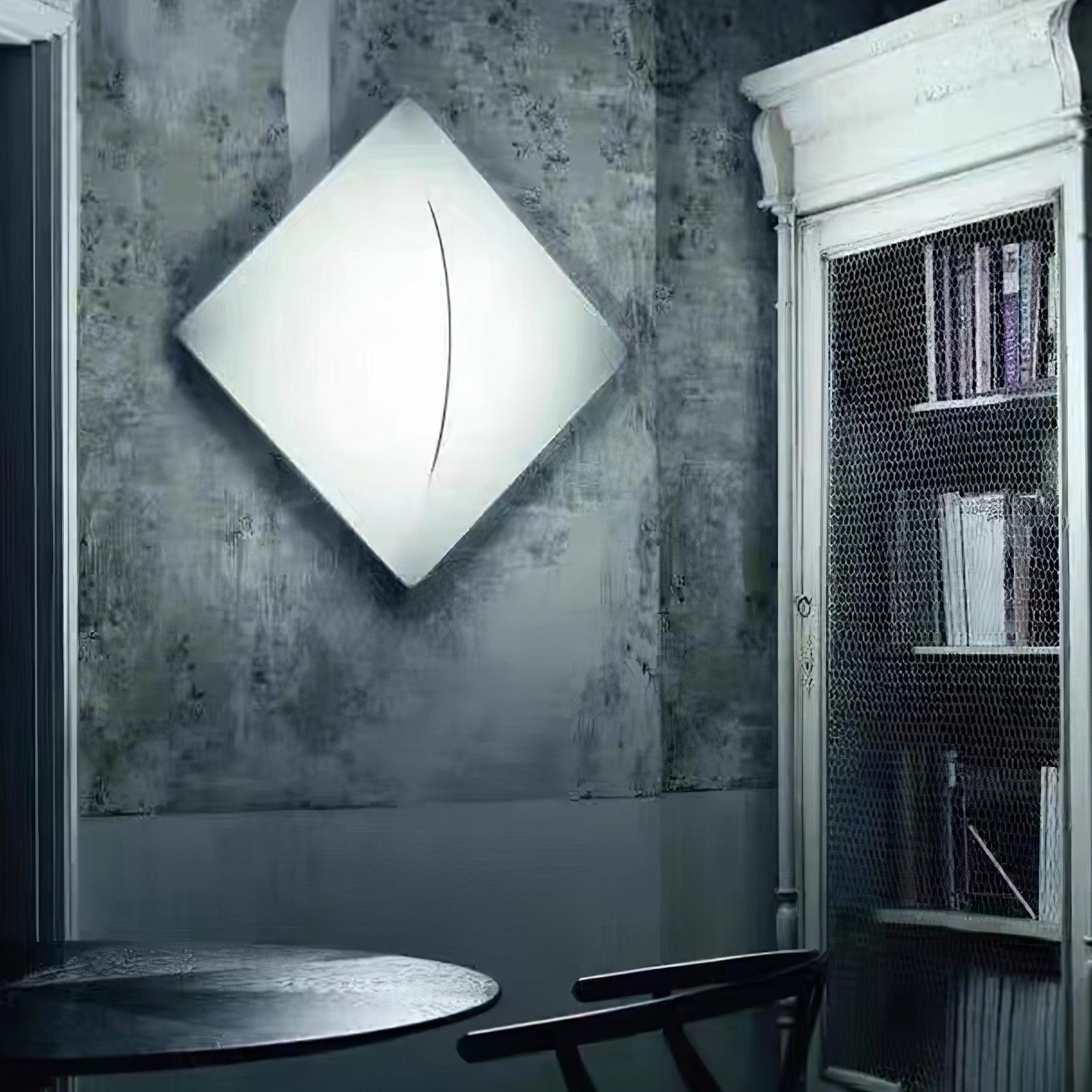 White diamond-oriented wall light beside a wire-front bookcase, round table and dark chair