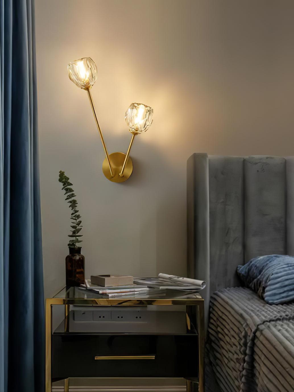 Portrait bedroom view of clear glass wall light beside a grey bed, blue curtain and glass-topped cabinet
