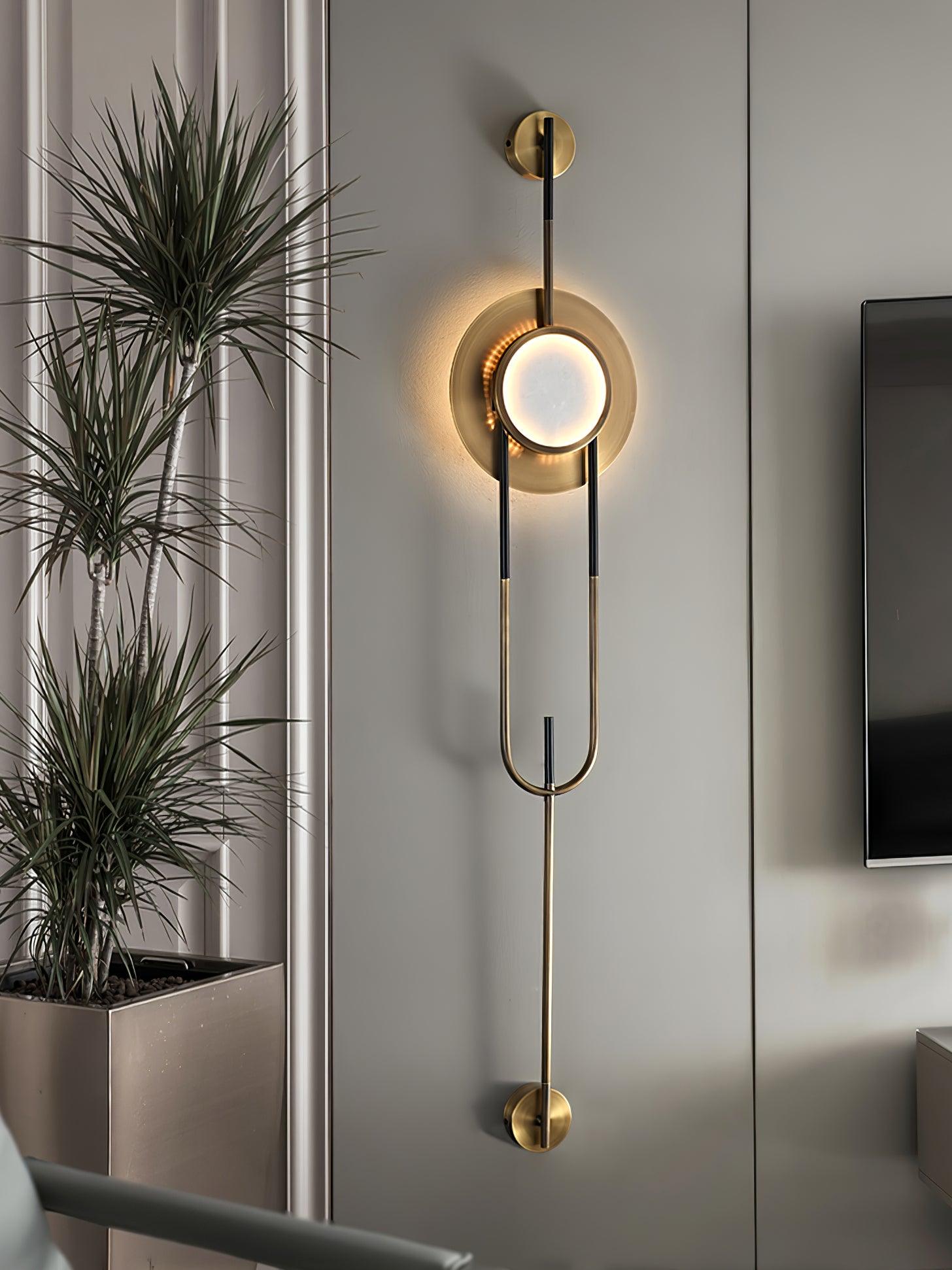 Tall illuminated marble wall light beside a television and a large potted plant