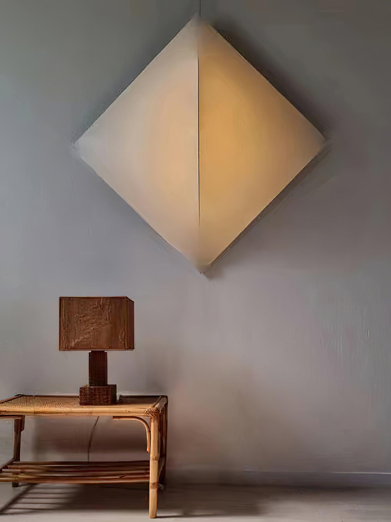 Diamond-oriented fabric panel with a curved face above a woven console and a separate box-shade table lamp