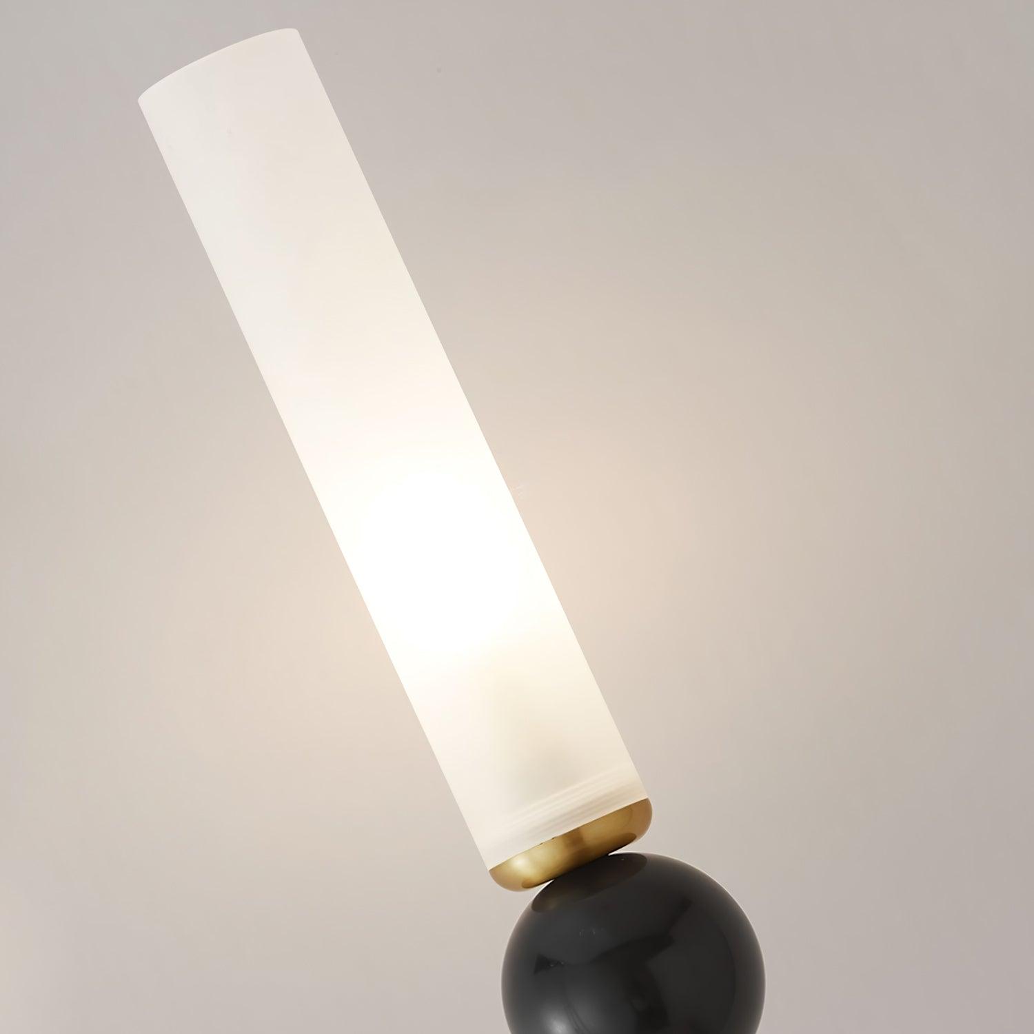 Angled close-up of glowing white cylindrical diffuser and brass collar above a glossy dark marble sphere
