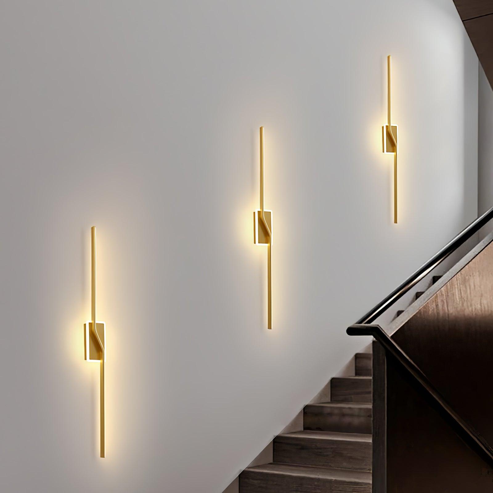 Three Gold strip lights along an indoor stair wall