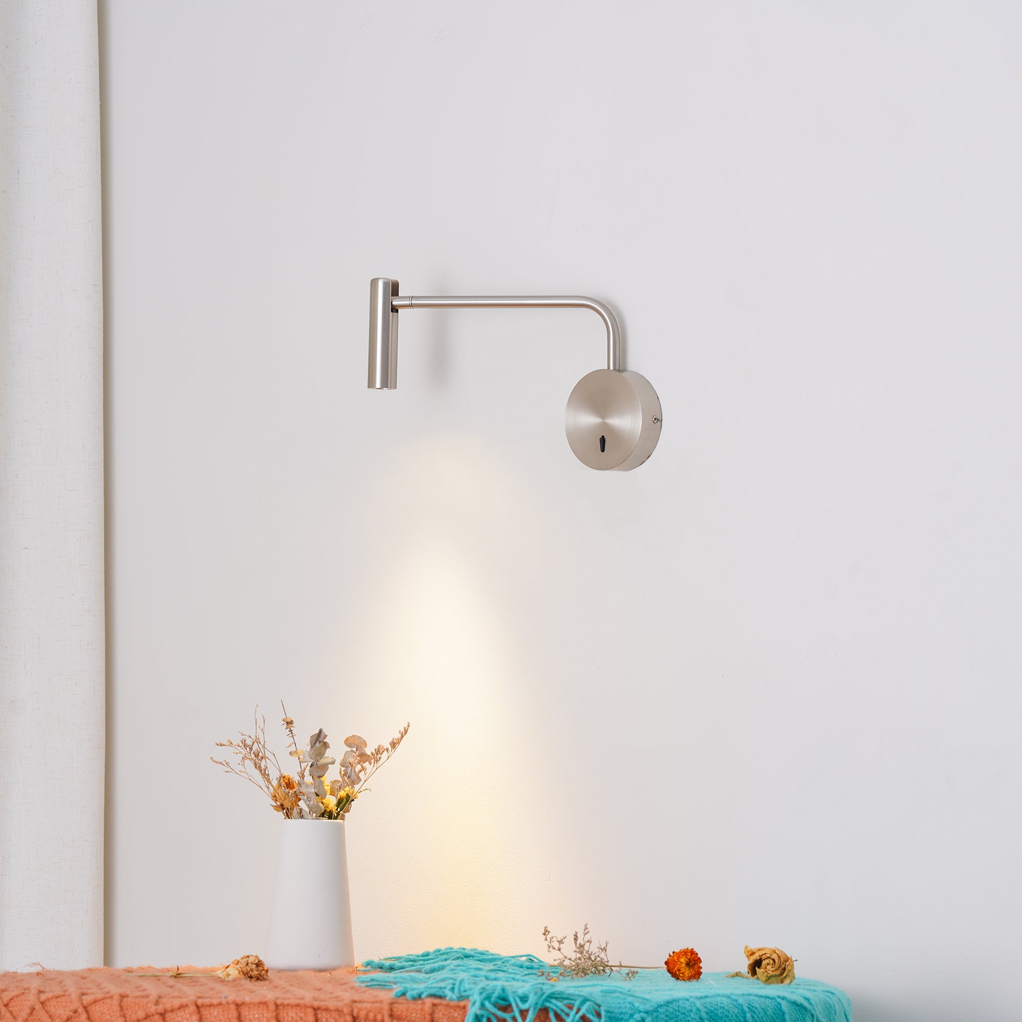 Sand Nickel wall light above a flower vase