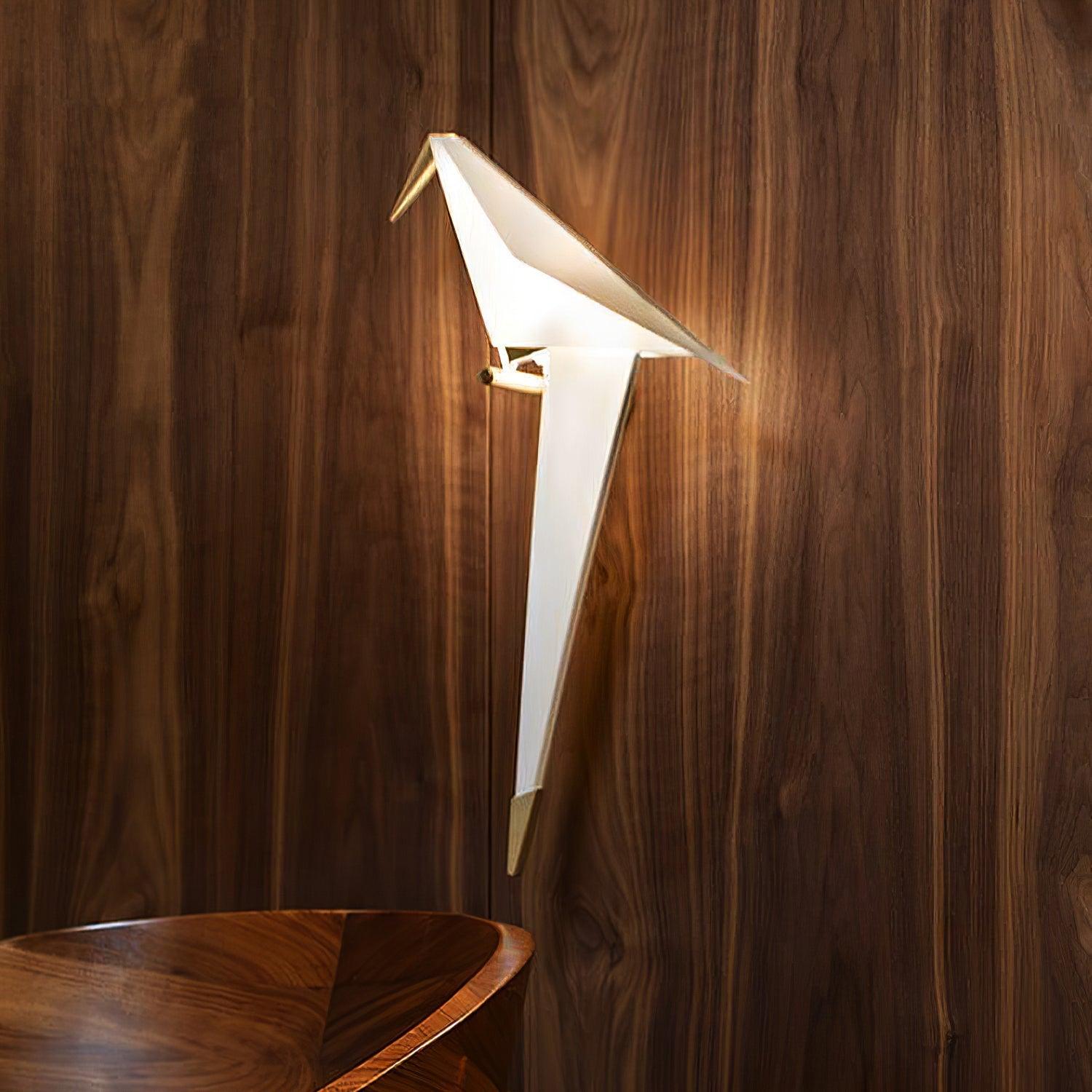 Glowing Gold and White bird wall light against wood-grain paneling above the edge of a wooden chair