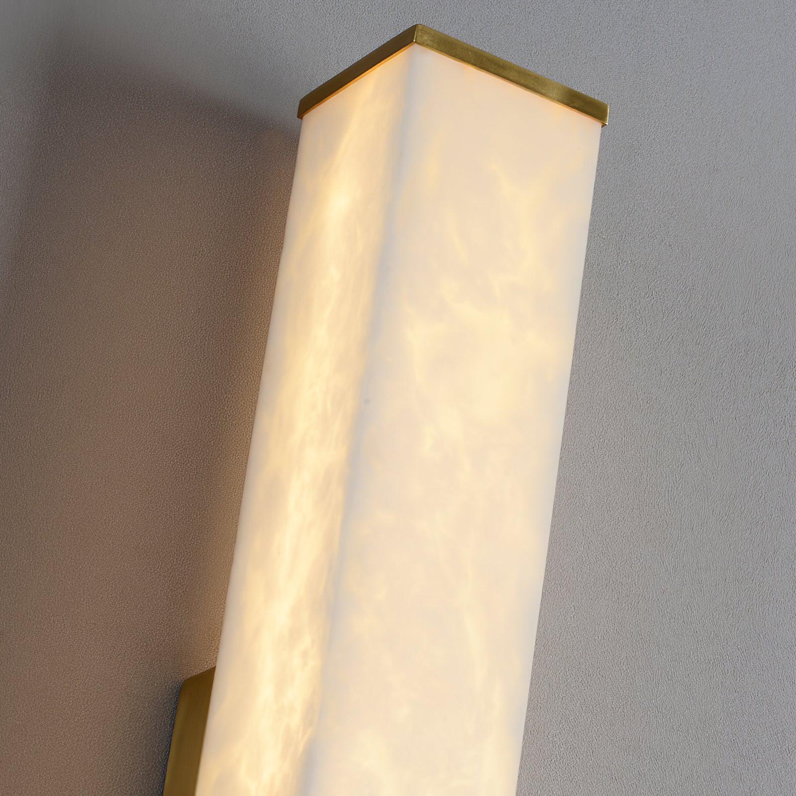 Close view of the illuminated stone cover meeting at a vertical corner beneath a thin brass top cap