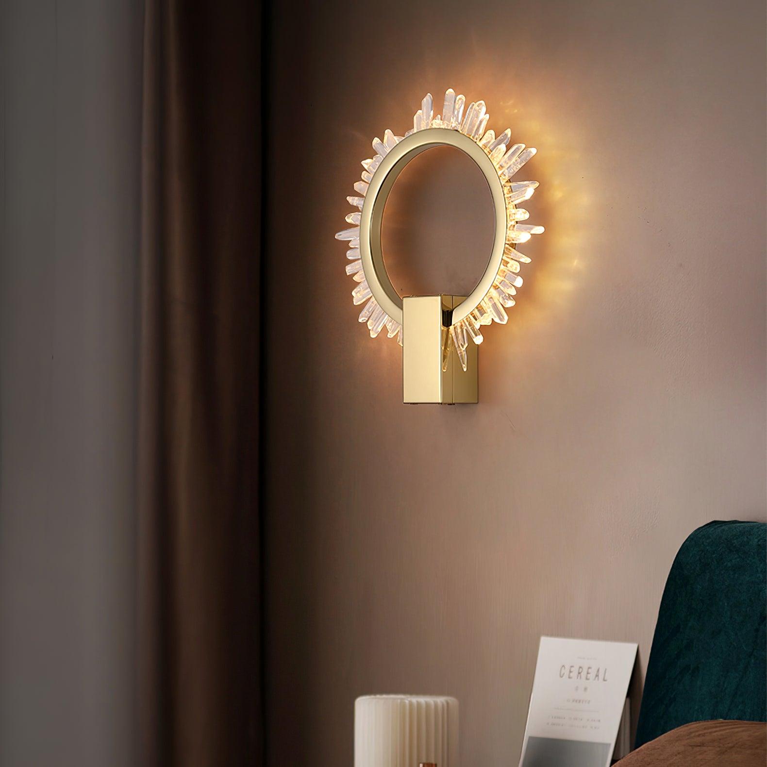 Angled lit crystal ring wall light beside a curtain and teal seat with a book below