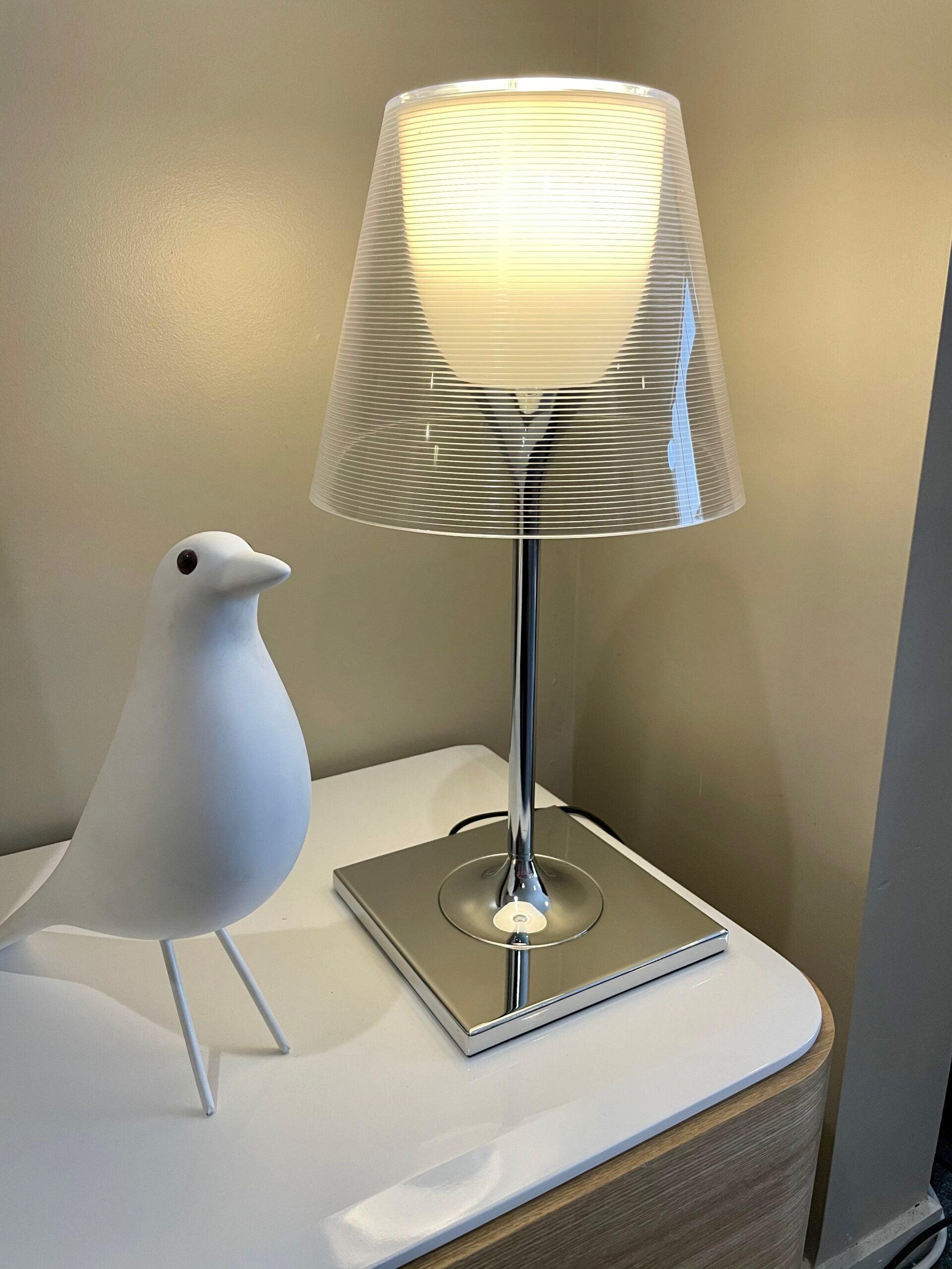 Chrome Prism lamp illuminated beside a bird ornament