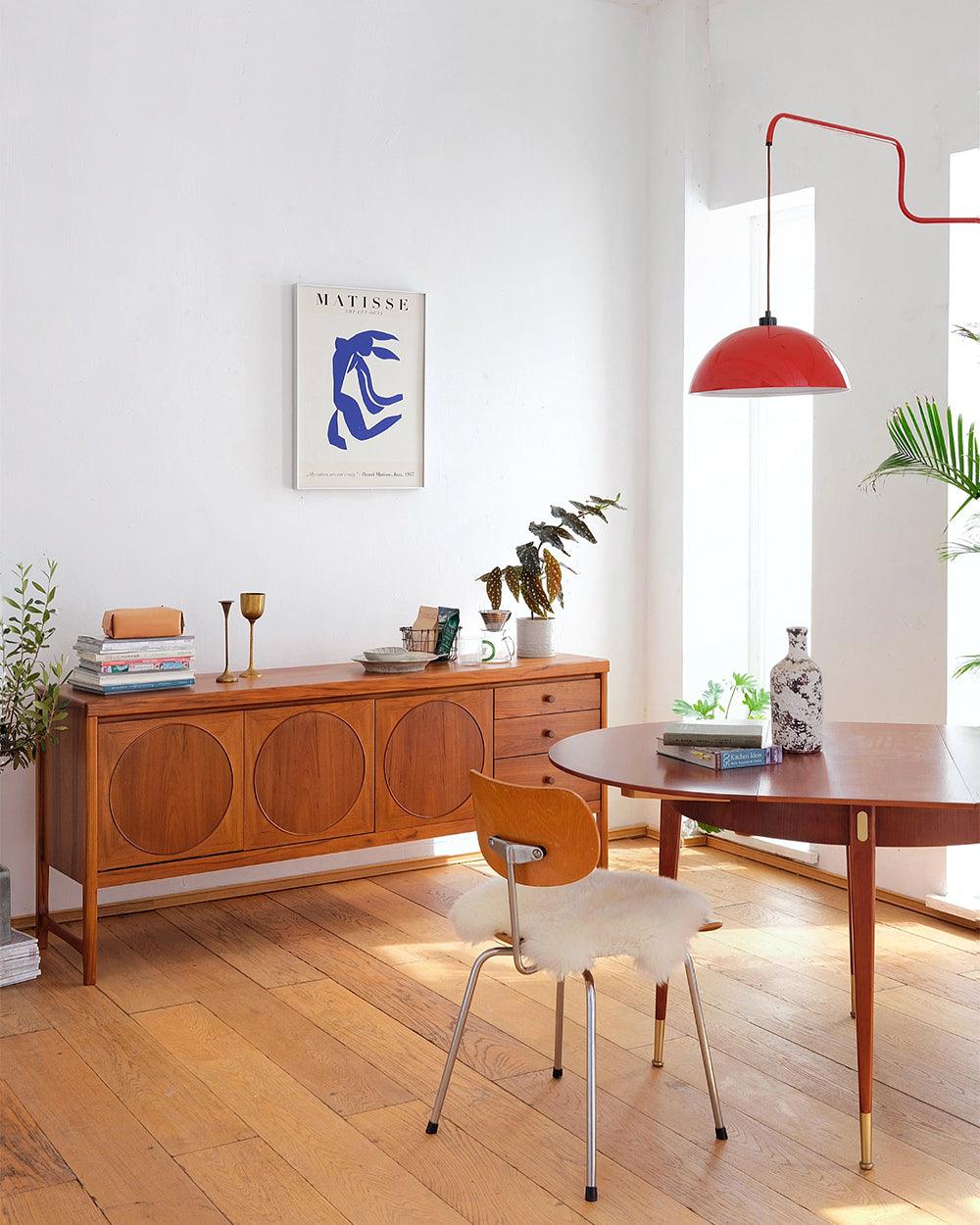 Long-arm wall lamp near a wooden dining cabinet