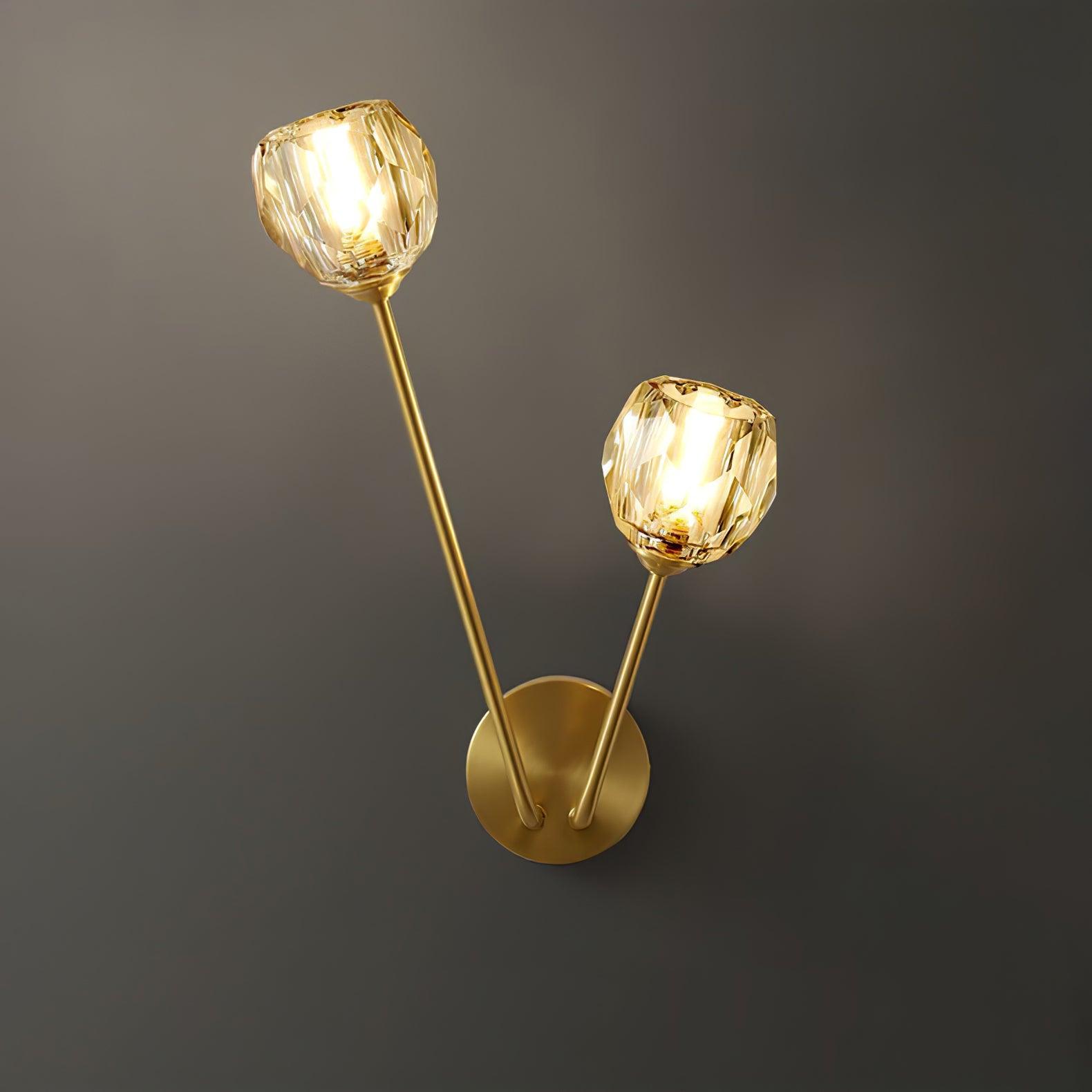 Close lit clear faceted shades with visible bright centres on two brass-tone stems against grey wall
