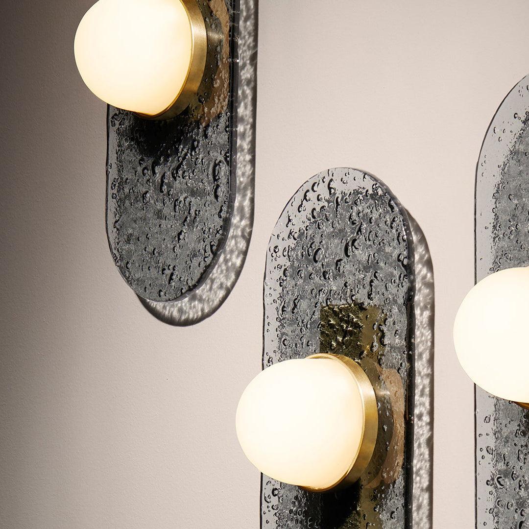 Close-up of glowing domes and textured glass panels casting reflected patterns on the wall