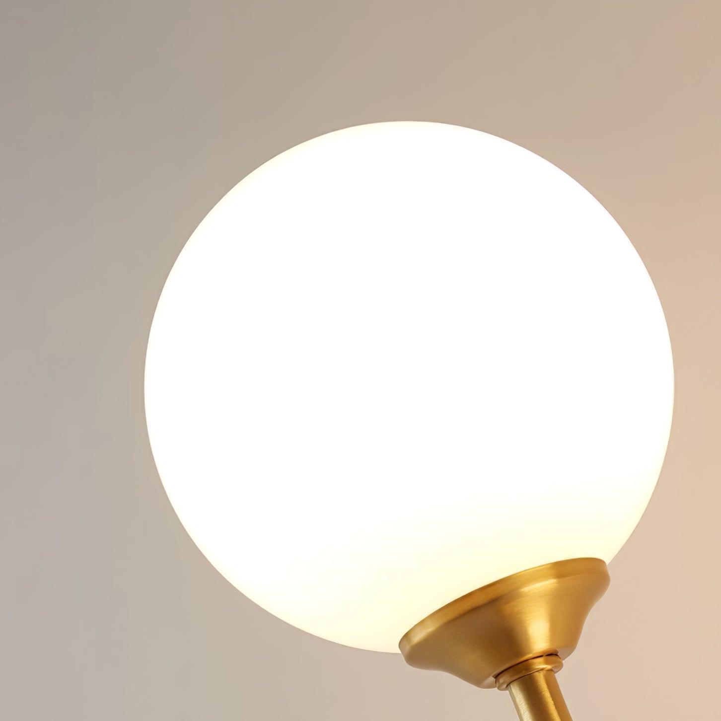 Close glowing white spherical glass shade in a brushed gold-tone cup on a stem