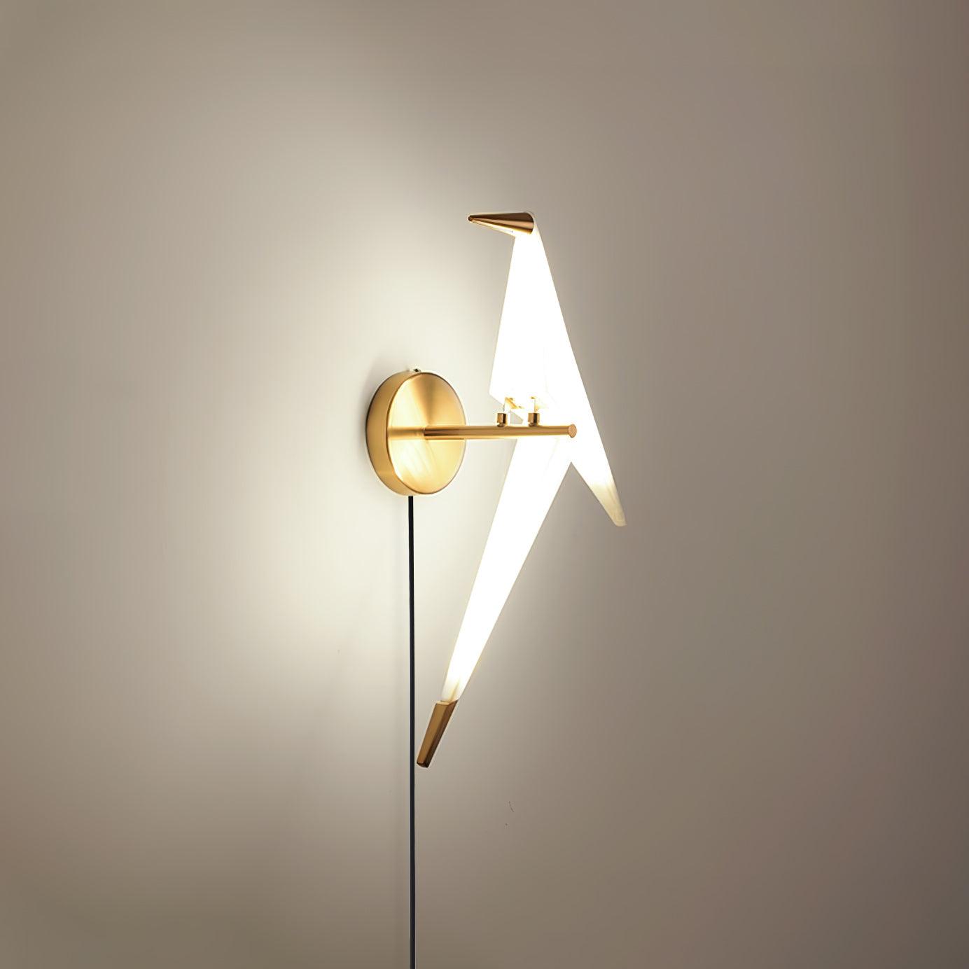 Gold and White bird wall lamp glowing above a round Gold backplate and Black cable, with its beak facing left
