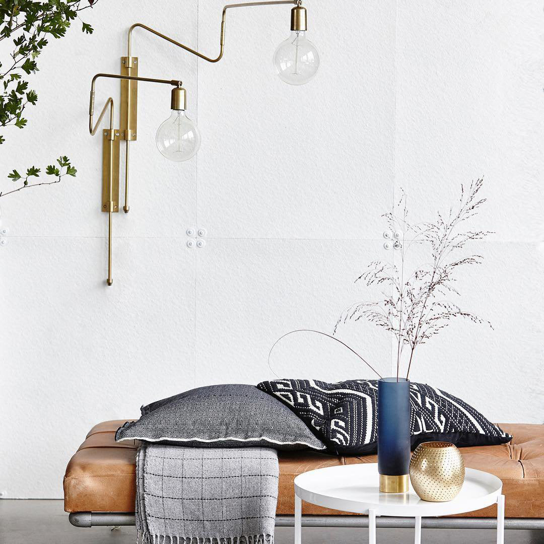 Brass Swing lamp near a brown leather bench