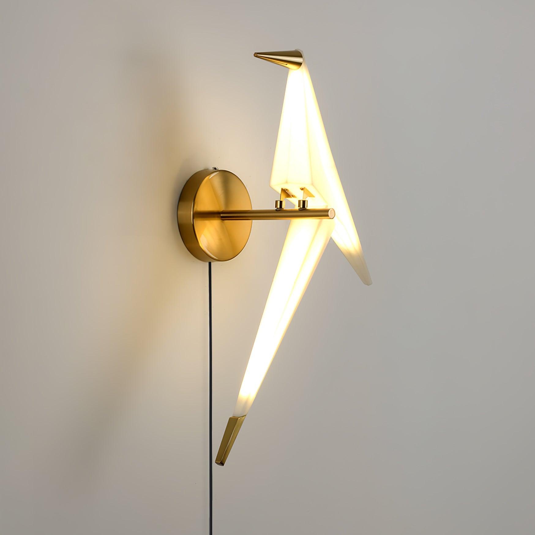 Rear angled view of the glowing White bird on a Gold wall arm and round backplate, with a Black cable and long Gold-tipped tail