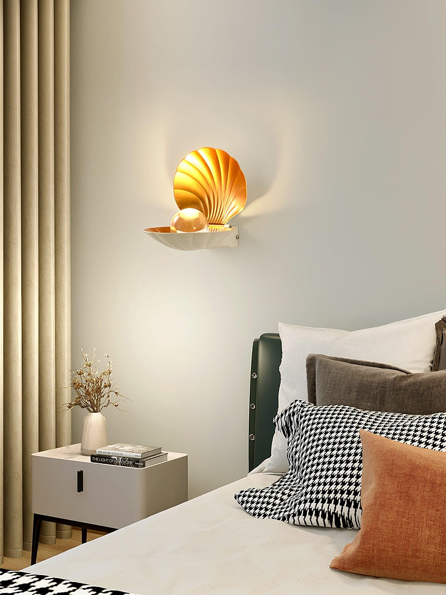 White clam-shaped wall light beside a padded headboard above a bedside cabinet