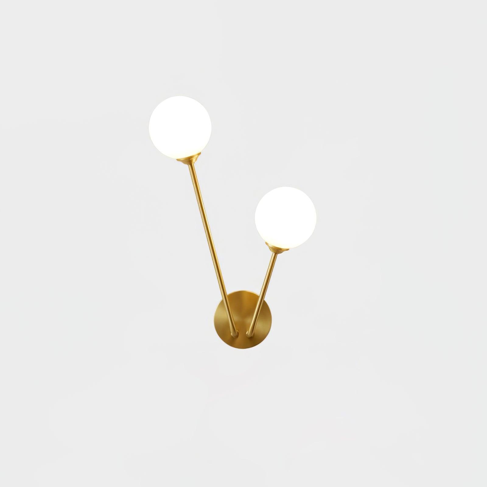 Isolated white two-globe wall light with unequal brass-tone stems and round plate on pale background
