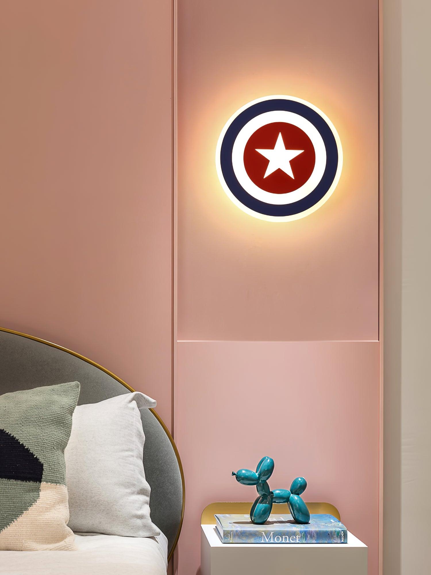 Star wall light on pink panelled wall above bedside cabinet with teal balloon-dog ornament and book