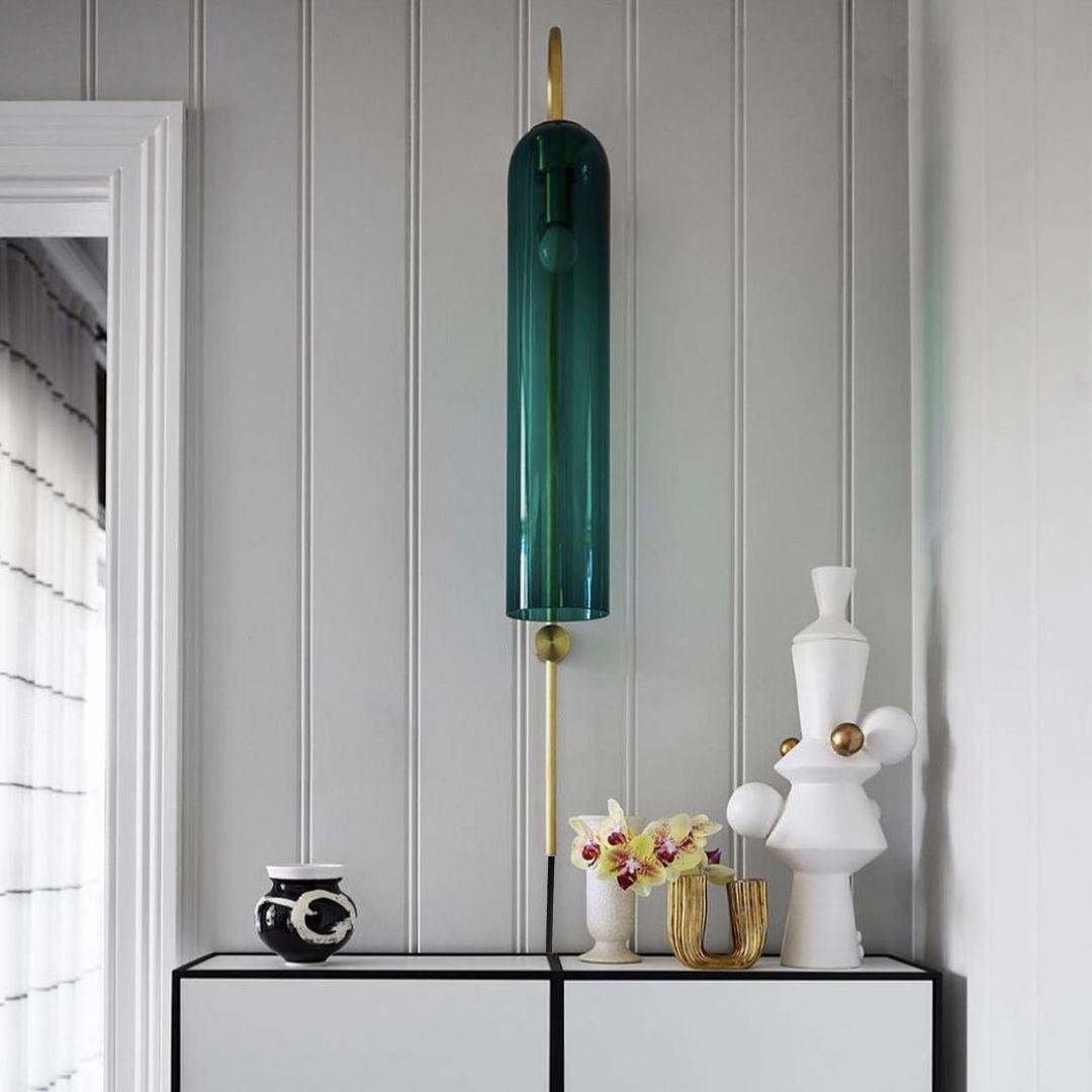 Dark glass wall lamp above a console