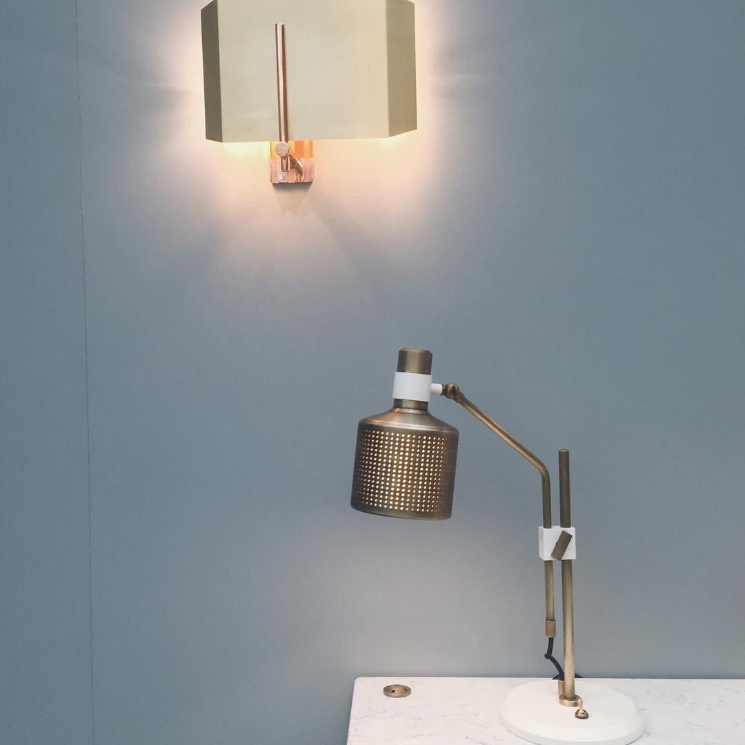 Lit gold-and-white single-head lamp on a marble counter beneath a separate rectangular wall light