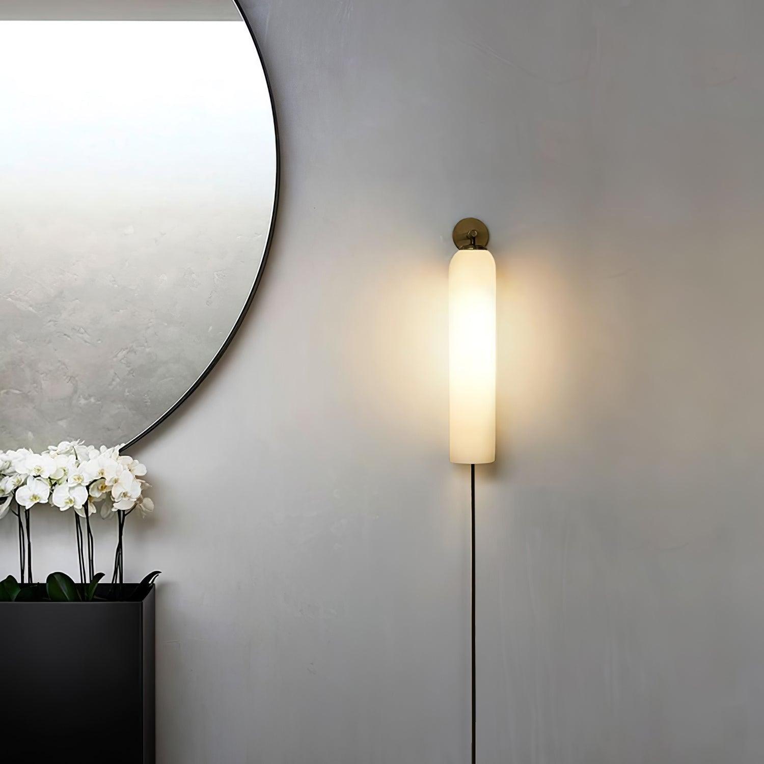 White cylindrical sconce beside a round mirror