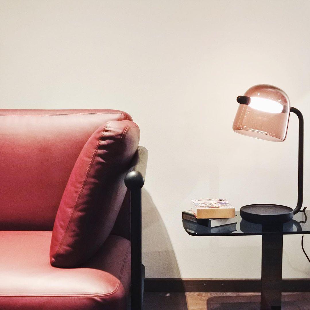 Mona dark-framed glass lamp beside a red sofa
